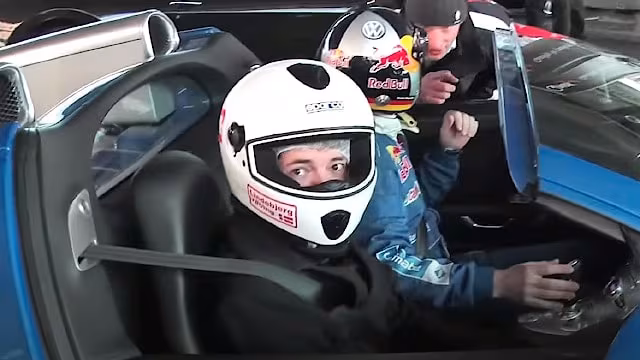Person med hjelm og køredragt sidder i en blå Bugatti Veyron Grand Sport sportsvogn.