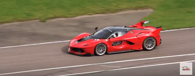 Rød Ferrari FXX K med nummer 23 kører i fart langs en racerbane med grøn græsskråning bagved.