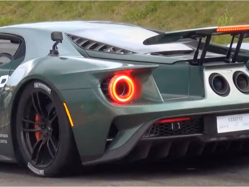Bagsiden af en grøn Ford GT sportsvogn med tændte baglygter og en stor bagvinge.