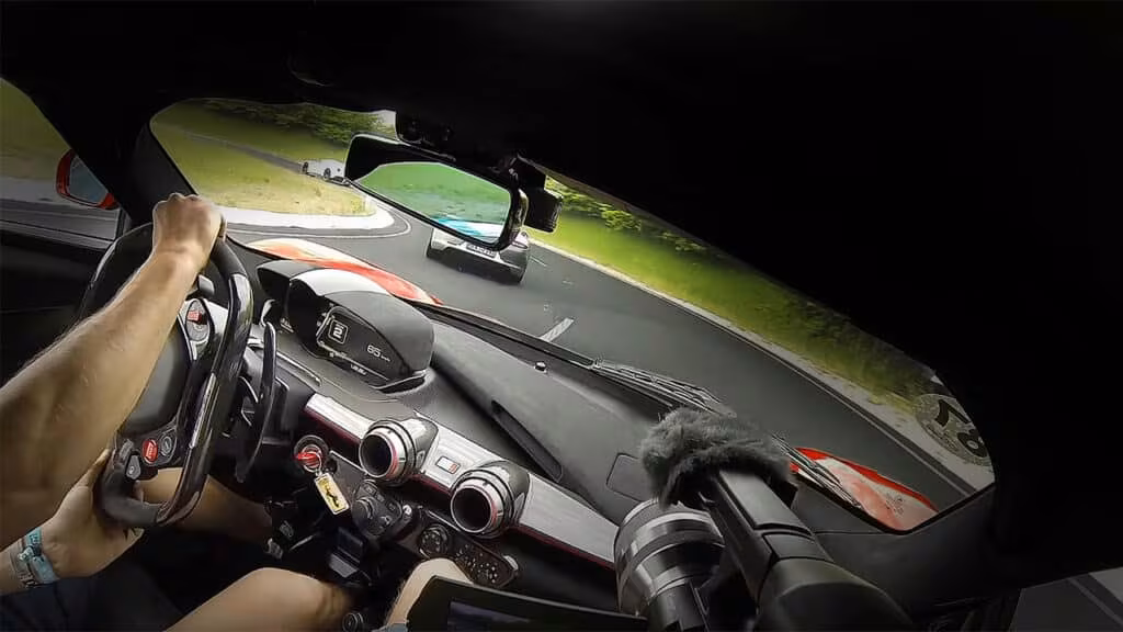 Udsigt fra førersædet af en Ferrari LaFerrari Aperta sportsvogn, der kører på en slynget bane efter en anden bil.